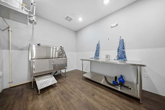 A clean, empty room with a stainless steel sink and a wooden floor.