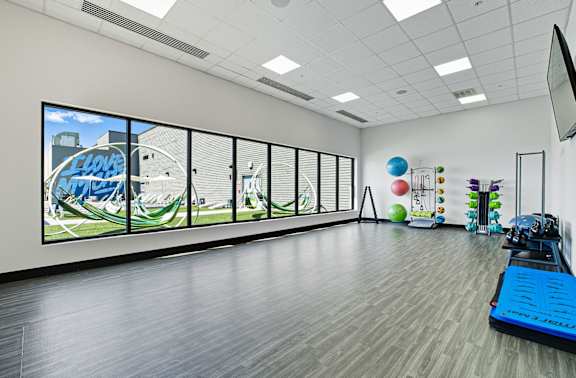 A gym with a treadmill, exercise balls, and a television showing a golf course.
