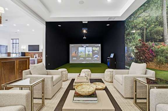 A living room with a large screen and a green space on the wall.