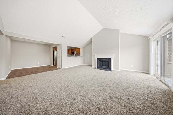 A spacious living room with a fireplace and a doorway leading to another room.
