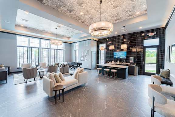 A modern living room with a large couch and a kitchen area in the background.