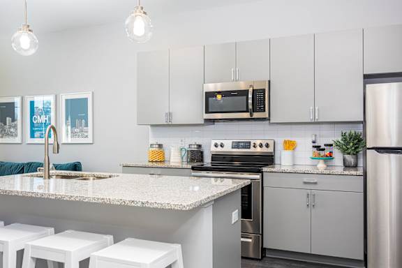 A kitchen with a white counter top and stainless steel appliances.