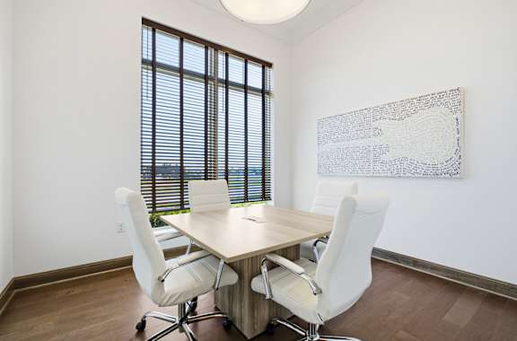 A conference room with a table, chairs, and a large window with blinds.