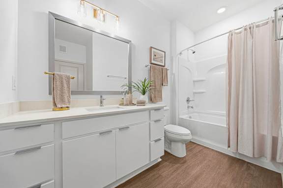 A white bathroom with a towel hanging on the mirror.