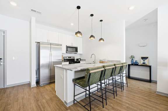 A kitchen with a white counter and green chairs.