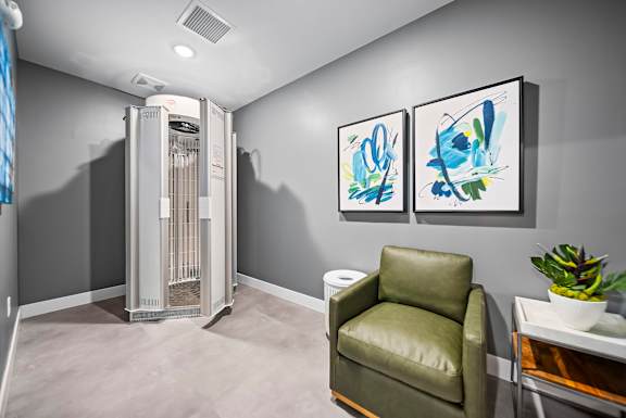 A room with a chair, a table, and two paintings on the wall.