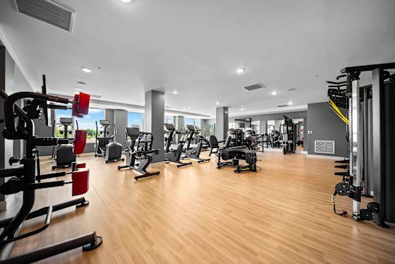 A gym with a variety of equipment including treadmills, weights, and exercise machines.
