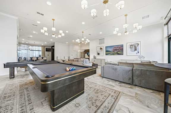 A pool table is in the middle of a room with a couch and a rug.