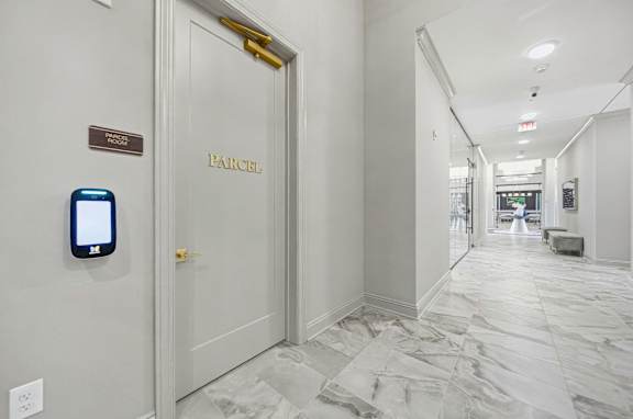 A hallway with a door labeled "PARCEL" and a smart device on the wall.