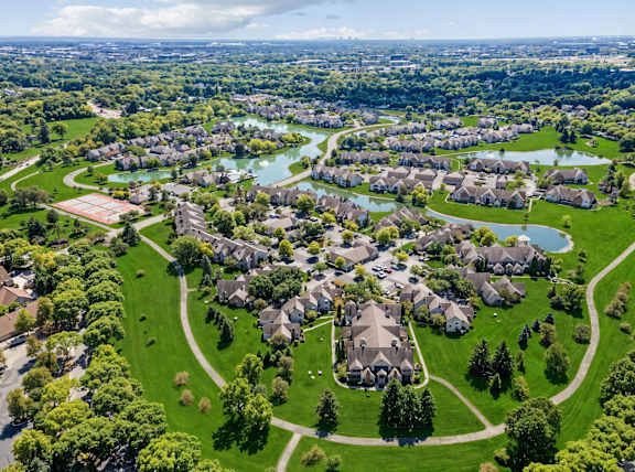 A bird's eye view of a residential area with houses, lawns, and a river.