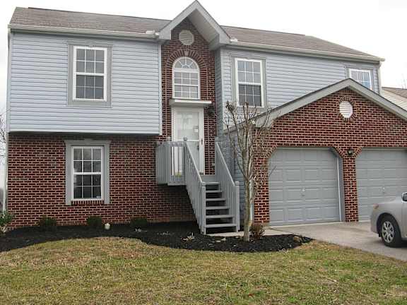 A house with a grey siding and a brick facade with a white door and windows.
