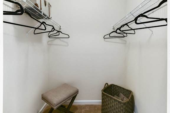 a closet with a chair and shoe racks on the wall