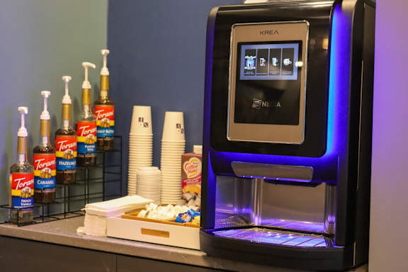 an atm machine on a counter next to a shelf of cups and other drinks