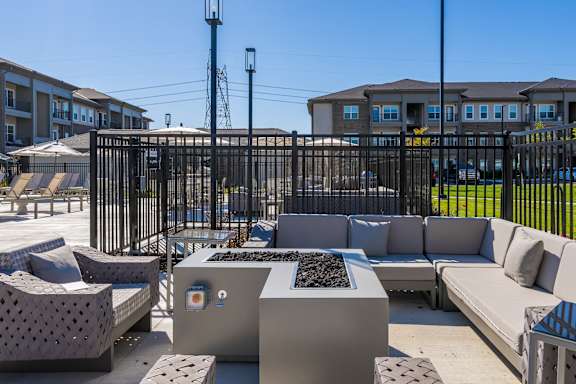 A black metal fence surrounds a concrete patio with a bench and a table.