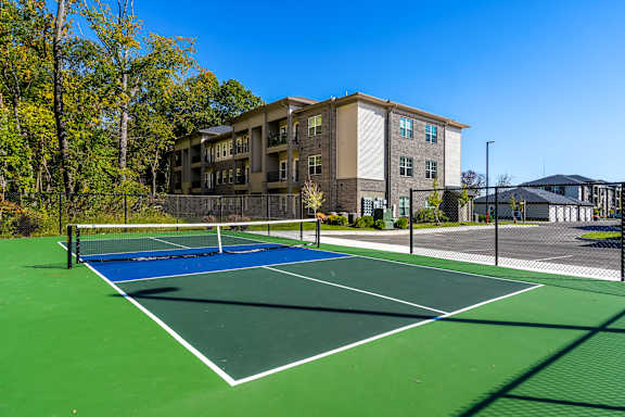 A tennis court is surrounded by apartment buildings.
