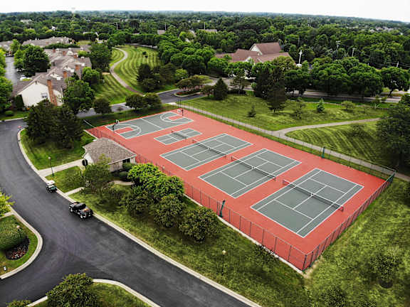 A red tennis court surrounded by a fence.