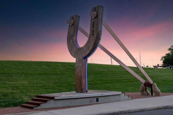 A large horseshoe-shaped sculpture is displayed in a park.