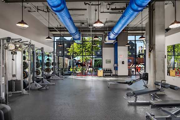 A gym with a variety of equipment including weights and benches.