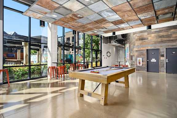 A pool table is in the middle of a room with a wooden ceiling.