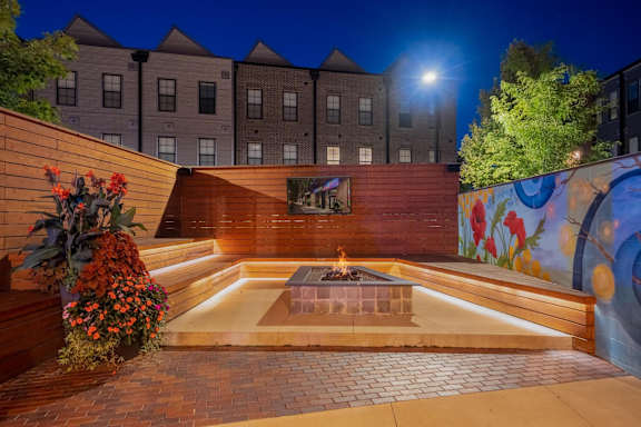 A fire pit in the middle of a brick patio surrounded by a wooden fence.