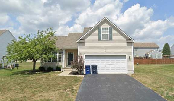 A house with a driveway and a tree in front of it.