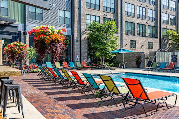 A row of colorful chairs are lined up by a pool.