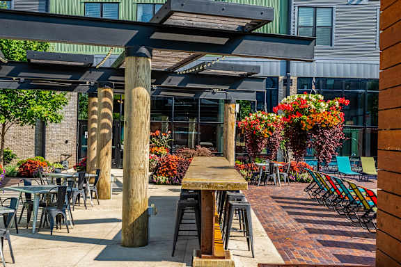 A patio with tables and chairs under a wooden pergola.