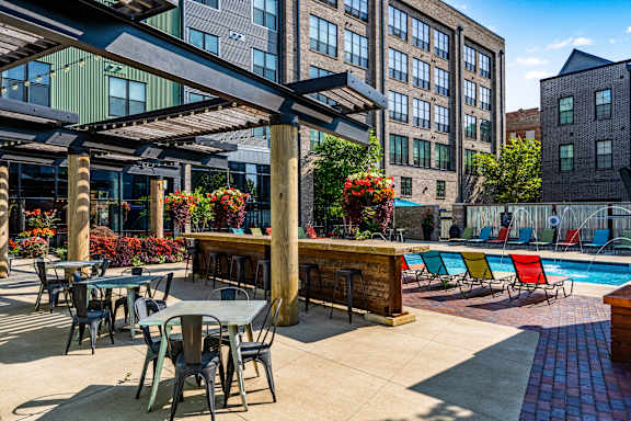 A poolside area with tables and chairs and a bar.
