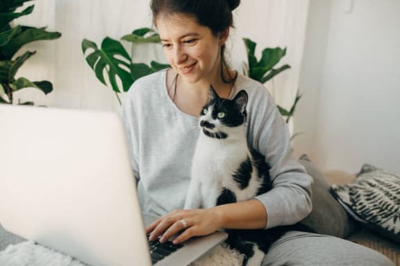 a woman with a cat sitting on her lap using a laptop computer