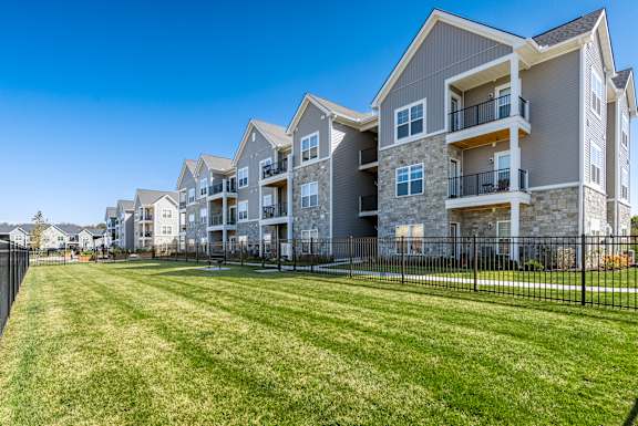 A row of modern apartment buildings with a green lawn in front.