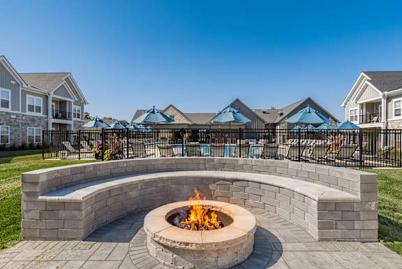 A fire pit sits in the middle of a brick patio.