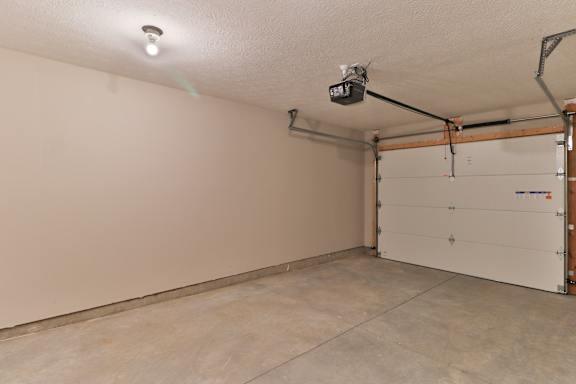 A garage with a white door and a security camera mounted on the ceiling.