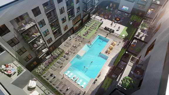 A large pool surrounded by lounge chairs and umbrellas is the centerpiece of a rooftop patio.