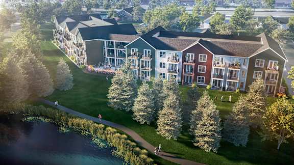 an aerial view of a building next to a body of water and trees