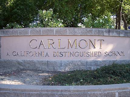 a sign for a distinguished school in front of trees