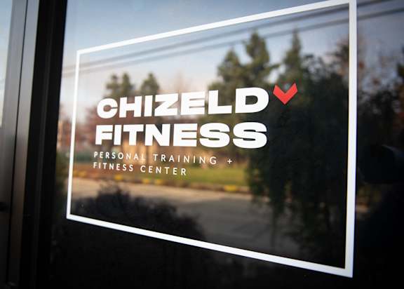 A window with a sign that says Chizeld Fitness Personal Training Fitness Center.