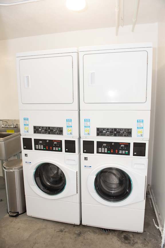 Two white front loading washing machines in a laundry room.