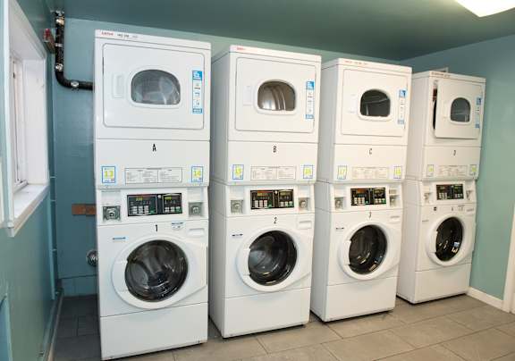 A row of white front load washing machines in a laundromat.