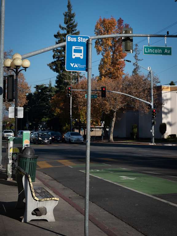 A bus stop sign is on a pole at the corner of Lincoln Av.