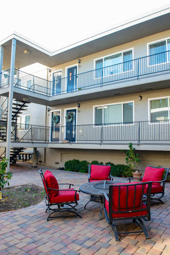 A patio with a table and chairs is in front of a building.