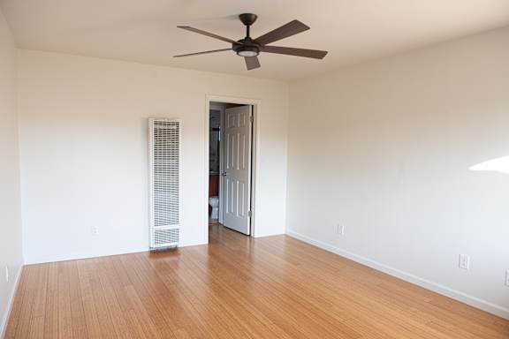 A room with a ceiling fan and a door leading to another room.