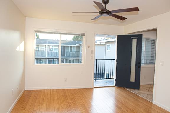 A room with a ceiling fan and a door leading to a balcony.
