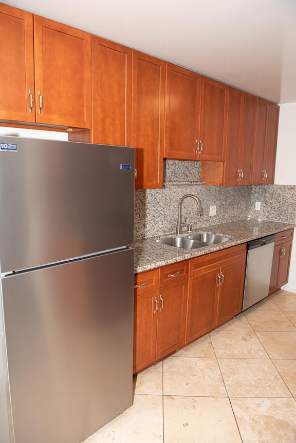 A kitchen with a stainless steel refrigerator and wooden cabinets.