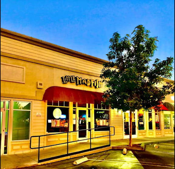 the front of a restaurant at night with a tree