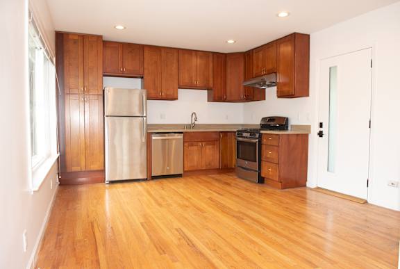 A kitchen with wooden cabinets and a stainless steel refrigerator.