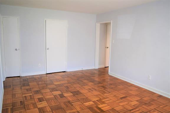 A room with white walls and a wooden floor with four doors.