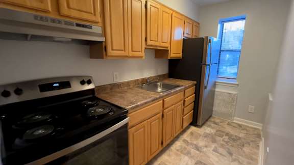 A kitchen with wooden cabinets and a black refrigerator.