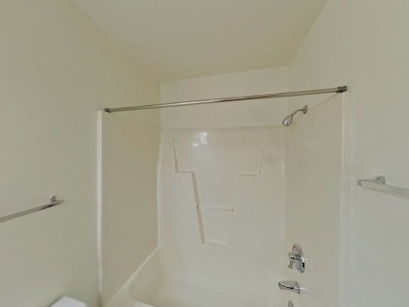 A white shower stall with a glass door and a metal grab bar.