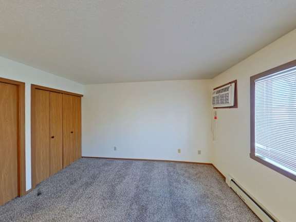 A room with a carpeted floor and a window with blinds.