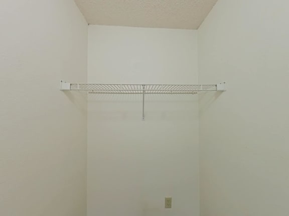 A white wall with a metal shelf attached to it.